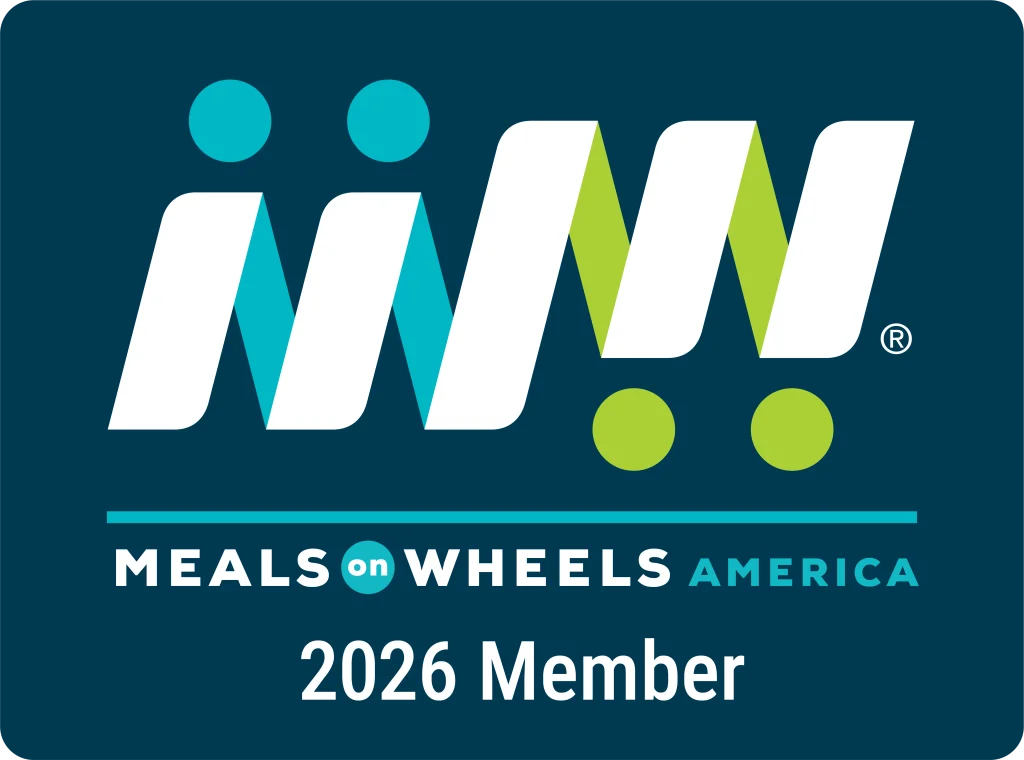 Meals on Wheels America 2026 Member badge featuring the organization’s logo with stylized letters and green and blue dots on a dark background.